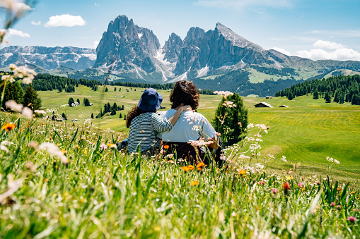 A couple is admiring the landscape in Seiser Alm, Dolomites. Alpe di Siusi with Langkofel mountain group in the background.