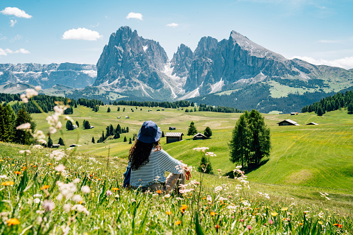 A woman is admiring the landscape in Seiser Alm, Dolomites. Alpe di Siusi with Langkofel mountain group in the background.