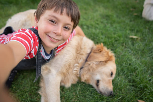 istock Happy little boy doing selfie with his dog on grass 1409554425