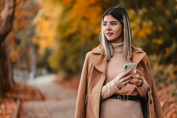 istock Young Woman Walking In The Park And Using Phone 1409556020