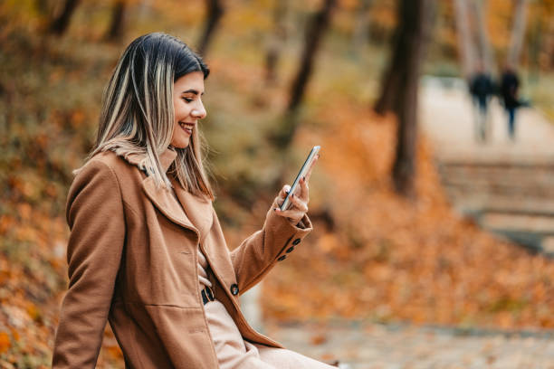 istock Young Woman Sitting In The Park And Using Phone 1409556164