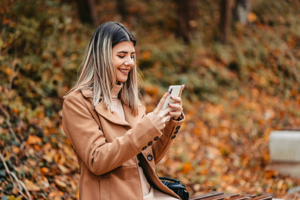 istock Young Woman Sitting In The Park And Using Phone 1409556257