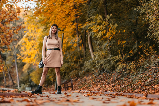 Profile of a beautiful young woman having a walk in the park during autumn.