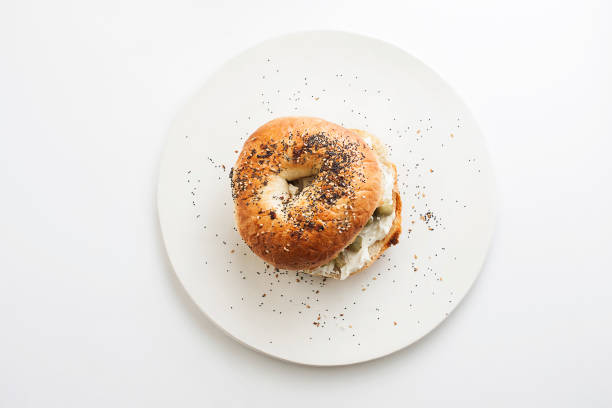 Everything Bagel topped with cream cheese and green olives Everything Bagel topped with cream cheese and green olives cream cheese photos stock pictures, royalty-free photos & images