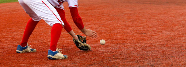 baseball-infielder, der den ball auf einem roten rasenfeld platziert - baseball player baseball sport catching stock-fotos und bilder