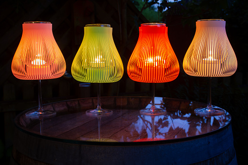 July 2022: Tea Candles, arranged  in multi-colored candle holders on a garden table, shining bright in the night