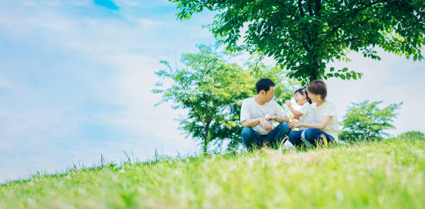 日当たりの良い緑地に座る親と子供 - 家族 日本人 ストックフォトと画像