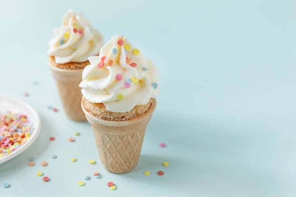 istock Two mini muffin cakes in ice cream cones on blue background 1409566106
