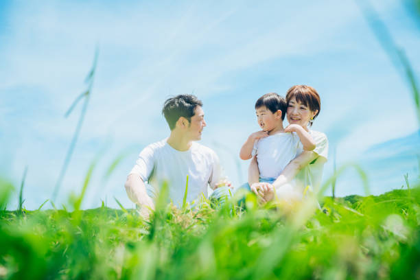 Parents and their child sitting on a sunny green space