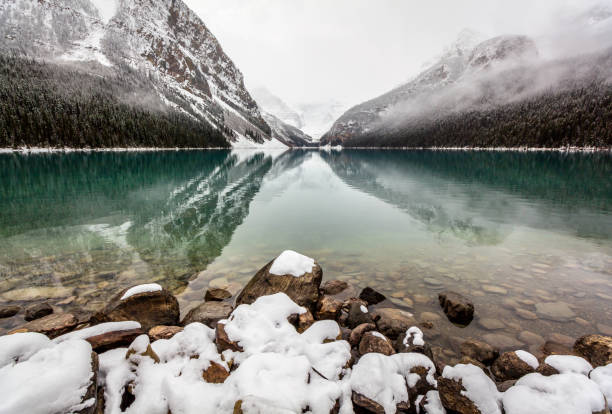Snow covered rocks at Lake Louise. Photo taken in fall after a fresh snowfall, before the water froze. Focus is on the rocks in the foreground, however the depth of field is quite large.