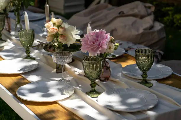 The table is set for a special celebration. The table is set. Empty plates and unusual glasses. Vintage tray, candleholder and vases with beautiful flowers. Close-up