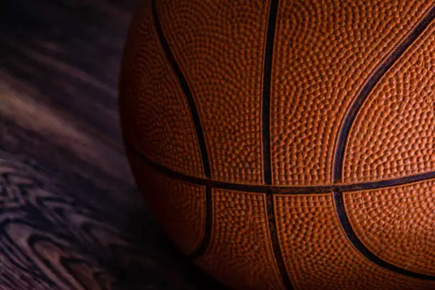 Basketball ball on floor. Basketball game detail. Orange basketball ball on dark background. Closeup of a basketball. NBA. Team sport. Finals