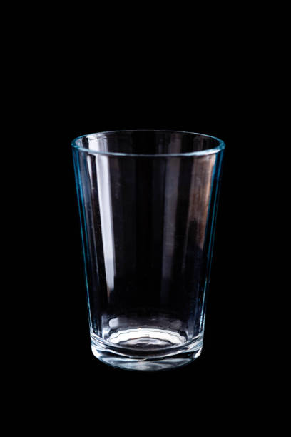 vetro trasparente vuoto su tavolo di sfondo nero senza liquido - tonalità di colore blu - night table flash foto e immagini stock