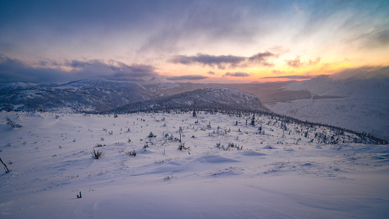Cielo colorido y luz solar mientras el sol se pone bajo el horizonte, sobre las montañas nevadas de Gaspesie photo