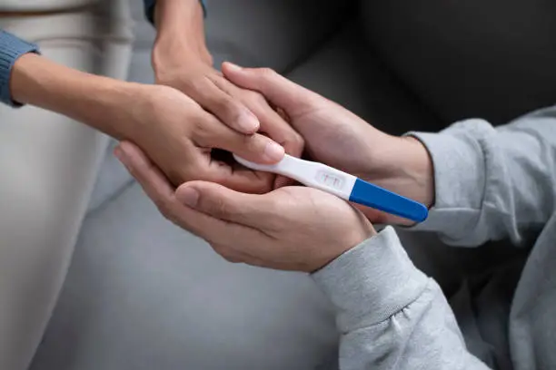 Happiness Asian couple holding positive pregnancy test on hand together. Family planning concept.