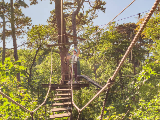 Rope park in wood forest.High-altitude climbing training on adventure track, equipped with safety straps and protective helmet.Adventure park close-up. Summer fun and sports for adventurous people. primer plano del parque de aventuras. diversión de verano y deportes para personas aventureras. parque de cuerdas en bosque de madera. entrenamiento de escalada a gran altitud en pista de aventura, equipado con correas de seguridad y casco protector.