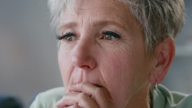 Closeup of a sad senior woman thinking. Lonely widowed lady looking unhappy and emotional, trying to cope with the loss, death of a loved one. Retired female with regret and sorrow on her face