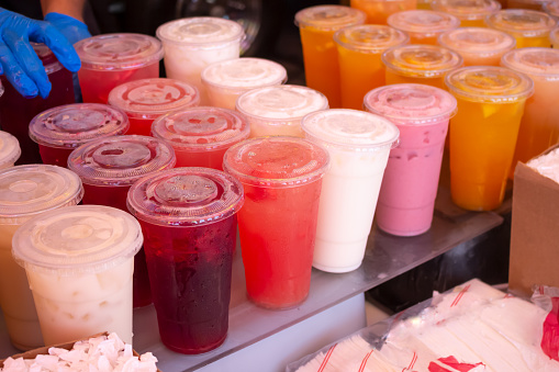 A view of several cups of aguas frescas at a Mexican marketplace.