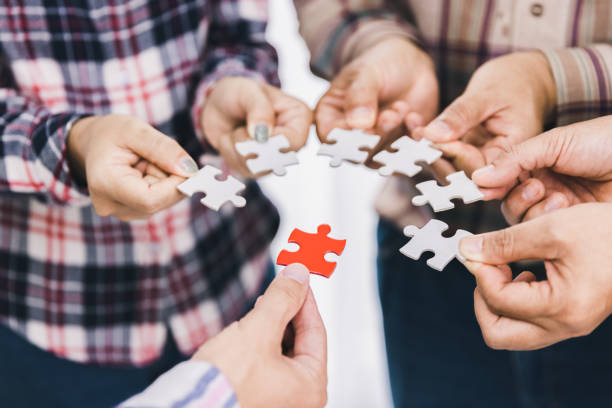 istock The concept of cooperation. A group of business people assembling jigsaw puzzle. teamwork, help and support in business. 1409592683
