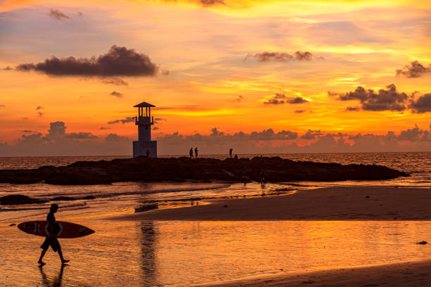 The scenery of the silhouette of Khao Lak Light Beacon in sunset time with the dramatic twilight sky at Nang Thong Beach, Phang Nga, Thailand. stock photo