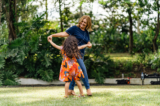 Mother and daughter dancing on the lawn in the park