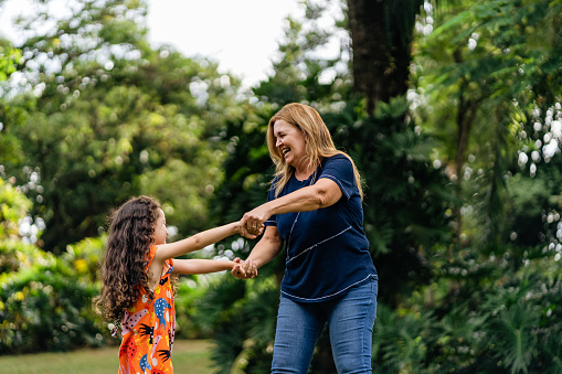 Mother and daughter dancing on the lawn in the park