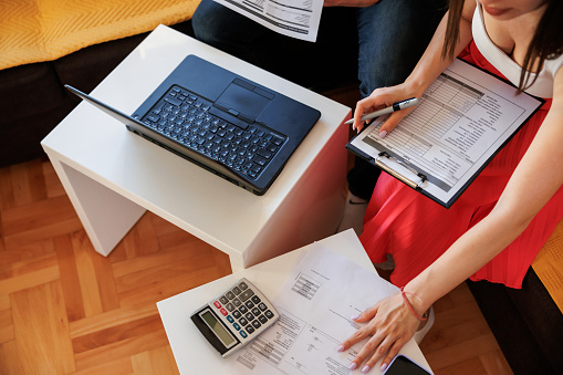 Young couple using a laptop and analyzing their finances with documents