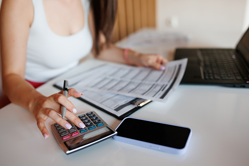 Close-up shot of unrecognizable young woman calculating and filling in the tax from at home