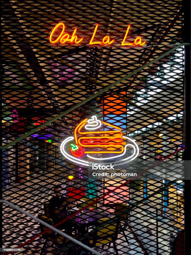 Ooh La La sweet cake symbol neon light invitation Food corner concept: Neon light advertisement. Set of neon signs. Glowing bulb banner hanging on grid background. Vertical composition with copy space. Fast delivery service neon logo signboard. Design template, modern trend design bright advertising, lighting banner. Advertisement Stock Photo