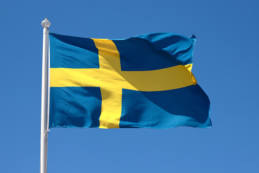 Close-up view of a hoisted Swedish flag against a clear blue sky.