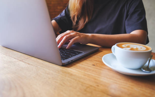 istock Closeup image of a young woman using and working on laptop computer with coffee cup on the table 1409607031