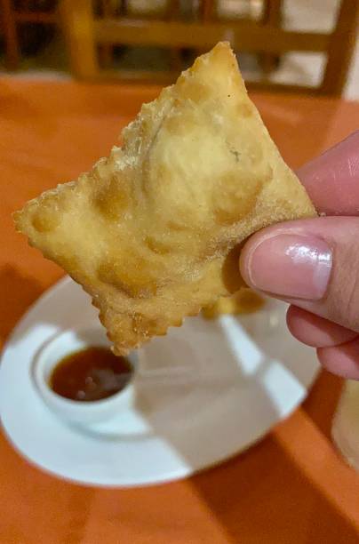 istock Pastel fried appetizer with red sauce held by hand close-up 1409608241