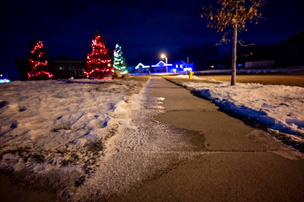 istock Ice and snow on a sidewalk at night with streetlight reflecting off the slick surface. 1409609352