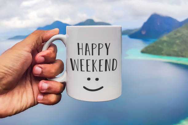 istock Weekend greeting on white coffee or tea cup in hand on sea background. Happy weekend 1409610008