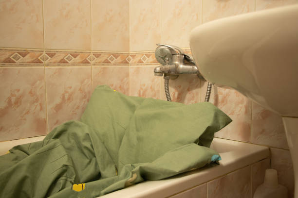 Sleeping in the bathroom inside the bathroom with a pillow and a blanket in Ukraine during rocket attacks over cities, the war in Ukraine, a protective place for people in the apartment