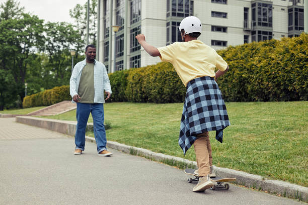 istock Boy riding on skateboard with his dad 1409614623