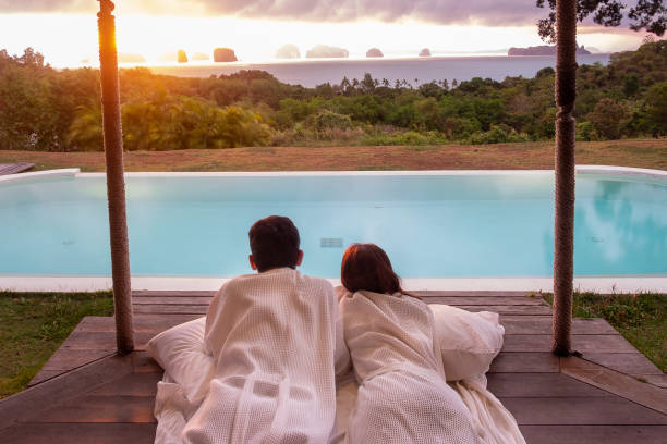 heureux couple voyageur profiter de la belle vue sur l’océan, les touristes se relaxant dans un complexe tropical de luxe avec piscine. ensemble, concept de lune de miel, d’amour, de voyage et de vacances d’été - honeymoon photos et images de collection