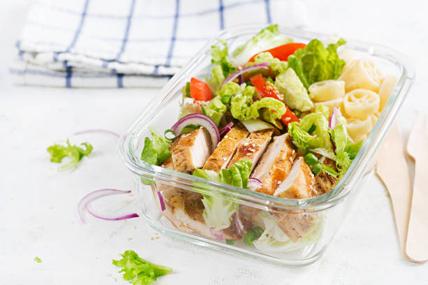 Lunchbox. Lunch box with grilled chicken fillet and pasta salad with fresh vegetables. stock photo