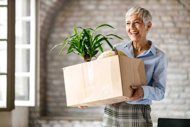 happy senior businesswoman carrying her belongings in the office. - firing unemployment downsizing box imagens e fotografias de stock