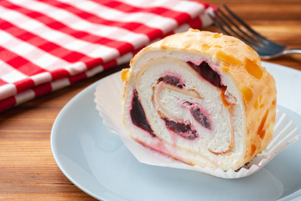 Meringue roll cake with cream on wooden table, close up