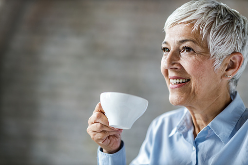 Portrait of mature woman enjoying in her coffee time. Copy space.