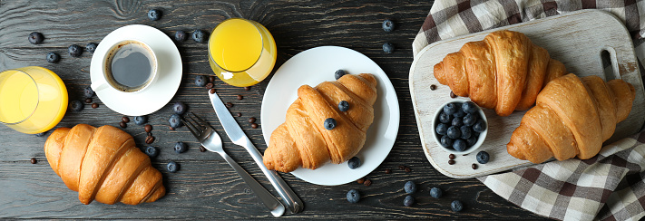 Concept of tasty breakfast with croissants on wooden background