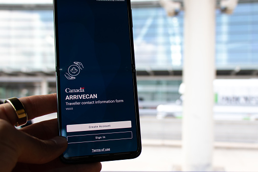 A passenger at Toronto Pearson is seen holding a smartphone with the ArriveCAN app on screen, used to enter Canada during the COVID-19 pandemic.