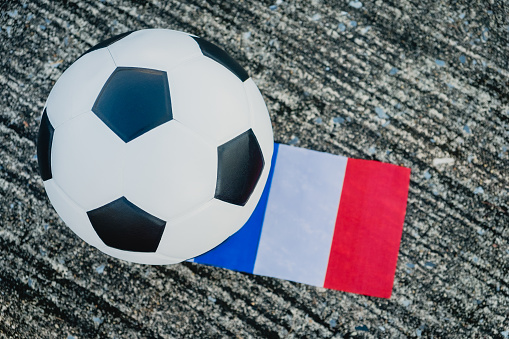 Above view of leather soccer ball with France national flag of the participating countries in the tournament on the street. Football equipment to play competitive game. Top-down