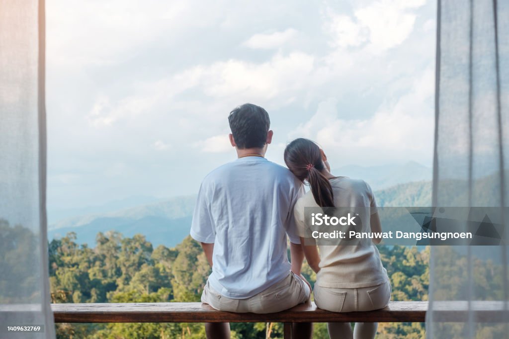 Couple tourist relaxing and looking mountain view at countryside home or homestay in the morning. Vacation, together travel, honeymoon, blogger, journey, trip and relaxing concept Couple - Relationship Stock Photo