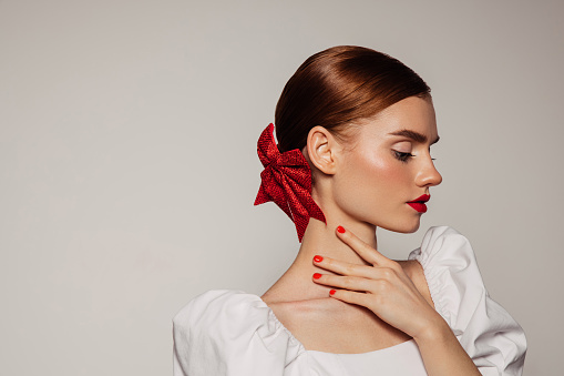 Woman with long hair, gloves, and red dress in profile on a white background