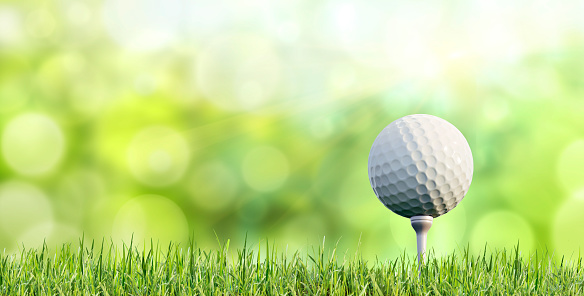 Drone perspective view of two golfers lining up their putts. They are in the beautiful surroundings of a golf course on the island of Moen in Denmark, surrounded by sand traps and water features. Horizontal format with some copy space.