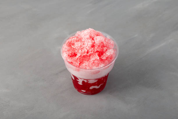 istock Red Slushie in disposable plastic cup on grey background, top view. Sweet Shaved ice. Spanish fruit granizado drink. Refreshing summer iced drink. 1409635115