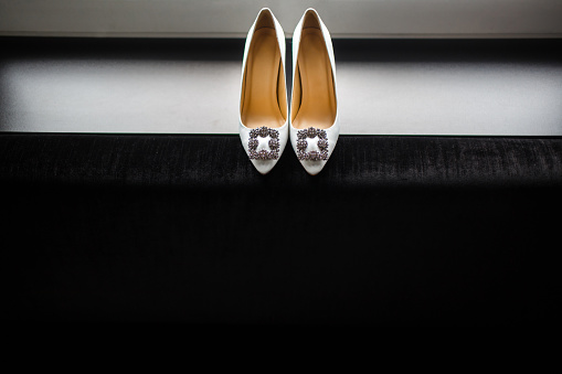 Ivory wedding shoes on a gray shelf.