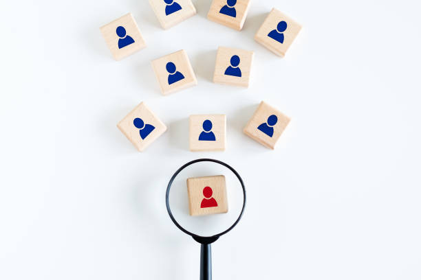 istock Magnifying glass looking for red employees icon on wood cube. 1409637066